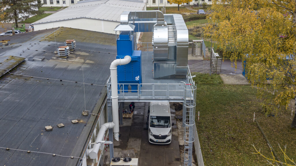 Energiesparendes Konzept: Die zentrale Be- und Entlüftungsan-lage (rechts) nutzt die Abwärme aus den Maschinen um die ein-strömende Außenluft, die in die Werkshalle geleitet wird, aufzu-heizen. Der Staubfilter (links) von Büchel entfernt effizient selbst kleinste Partikel aus der abgesaugten Luft.